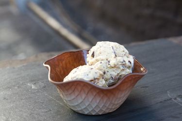 A glass ice cream dish with a waffle cone pattern filled with almond joy ice cream.