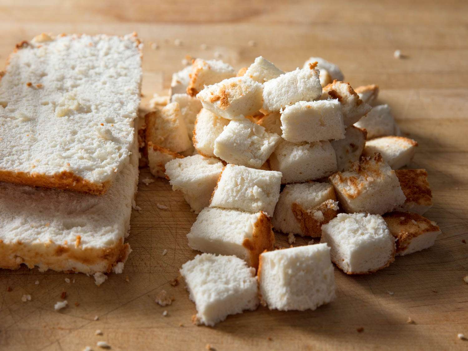 Angel food cake being cut into cubes.