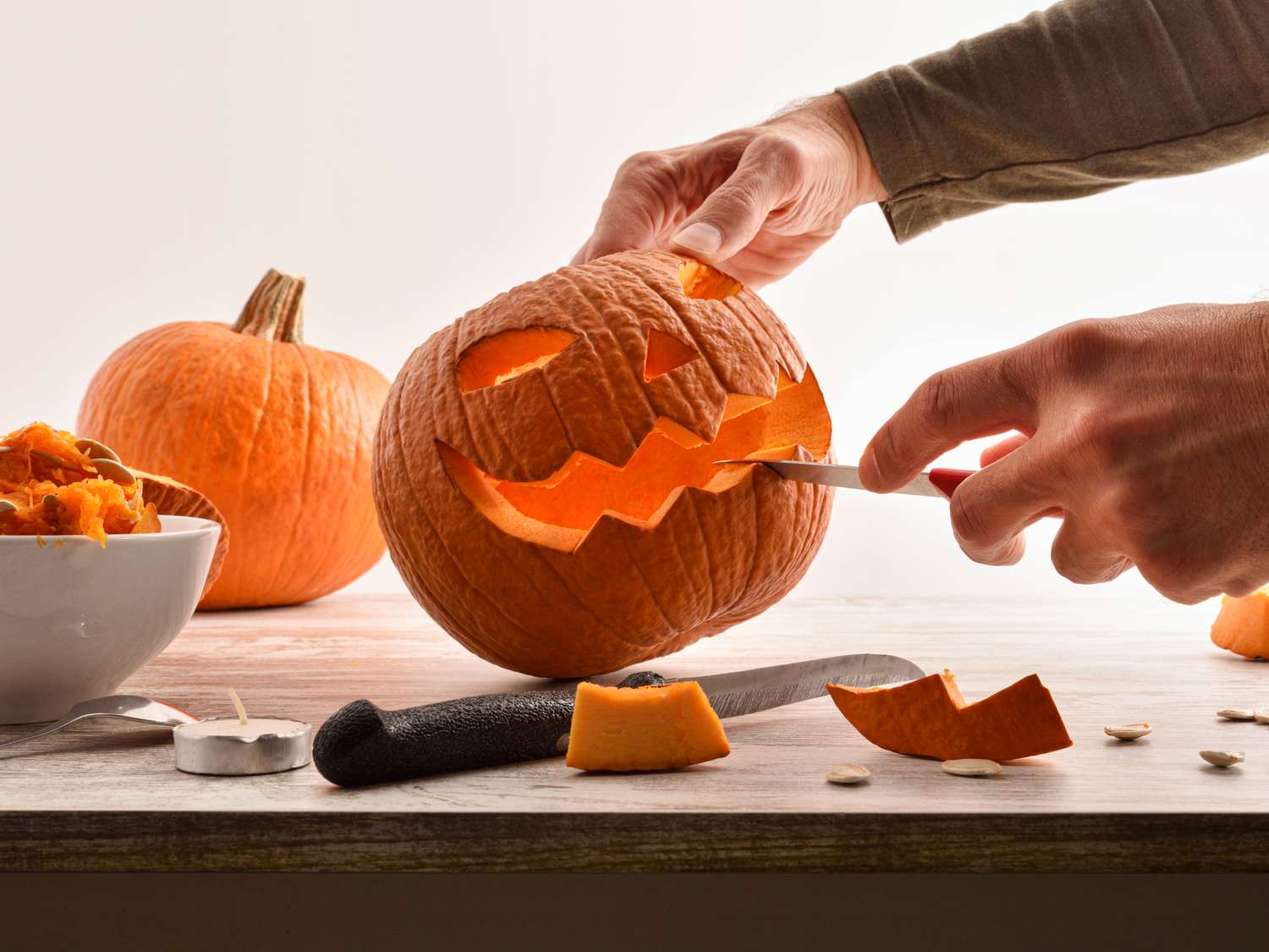 A person carving a jackolantern face on a pumpkin using a knife