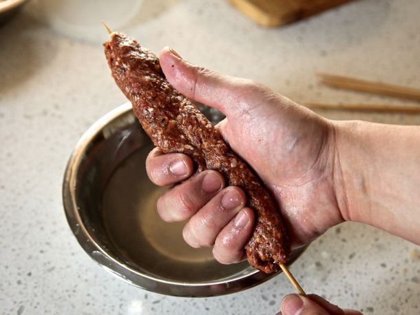 Shaping kebab meat mixture into skewers. 