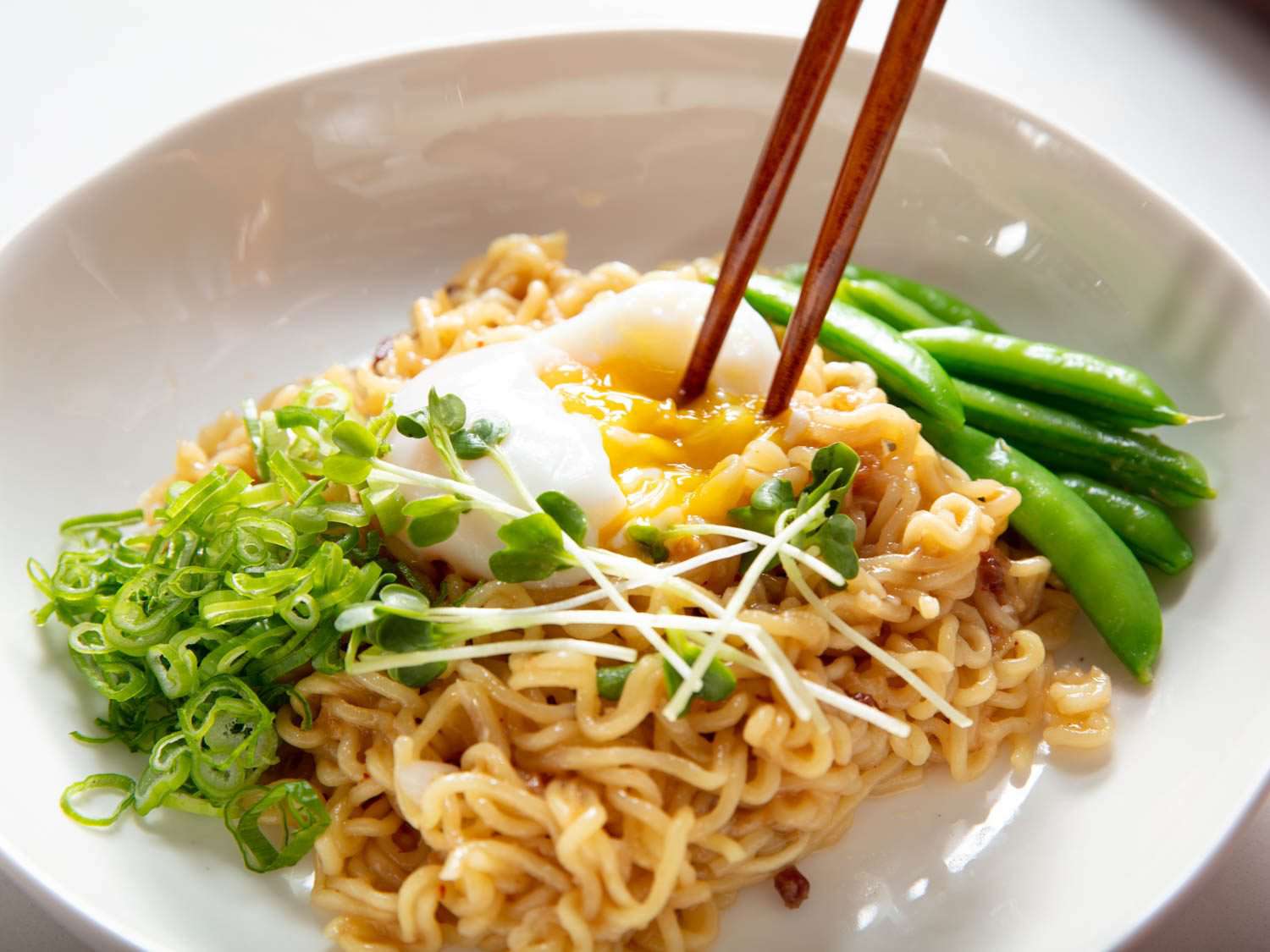 Chopsticks breaking an onsen egg set atop XO mazemen made with instant noodles.