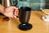 A person picking the Ember mug off of its charging platform.