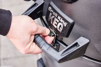 A person unlocks the Broil King Keg Kamado Charcoal Grill