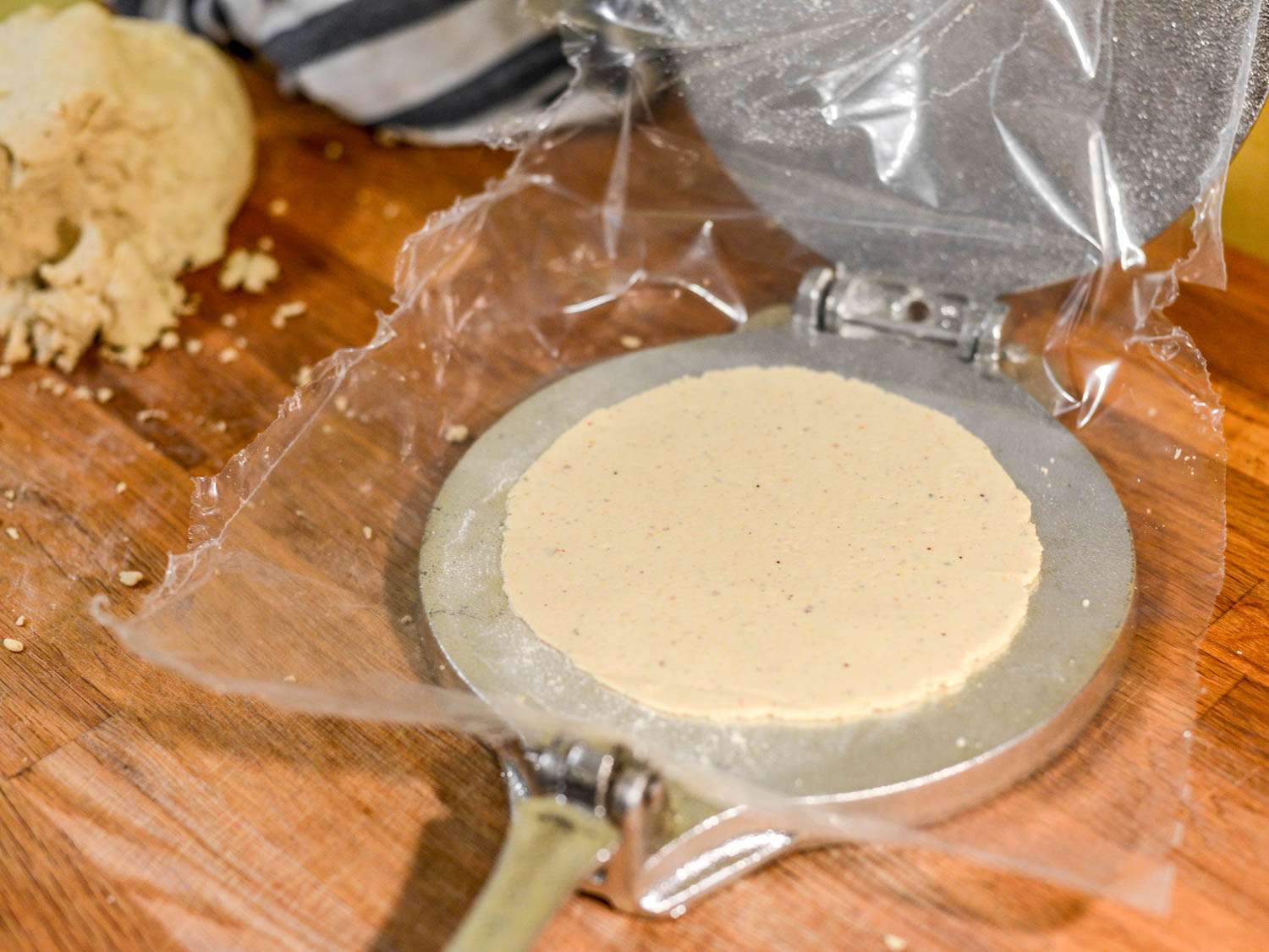 Masa dough being pressed in a tortilla press for San Antonio-style tacos.