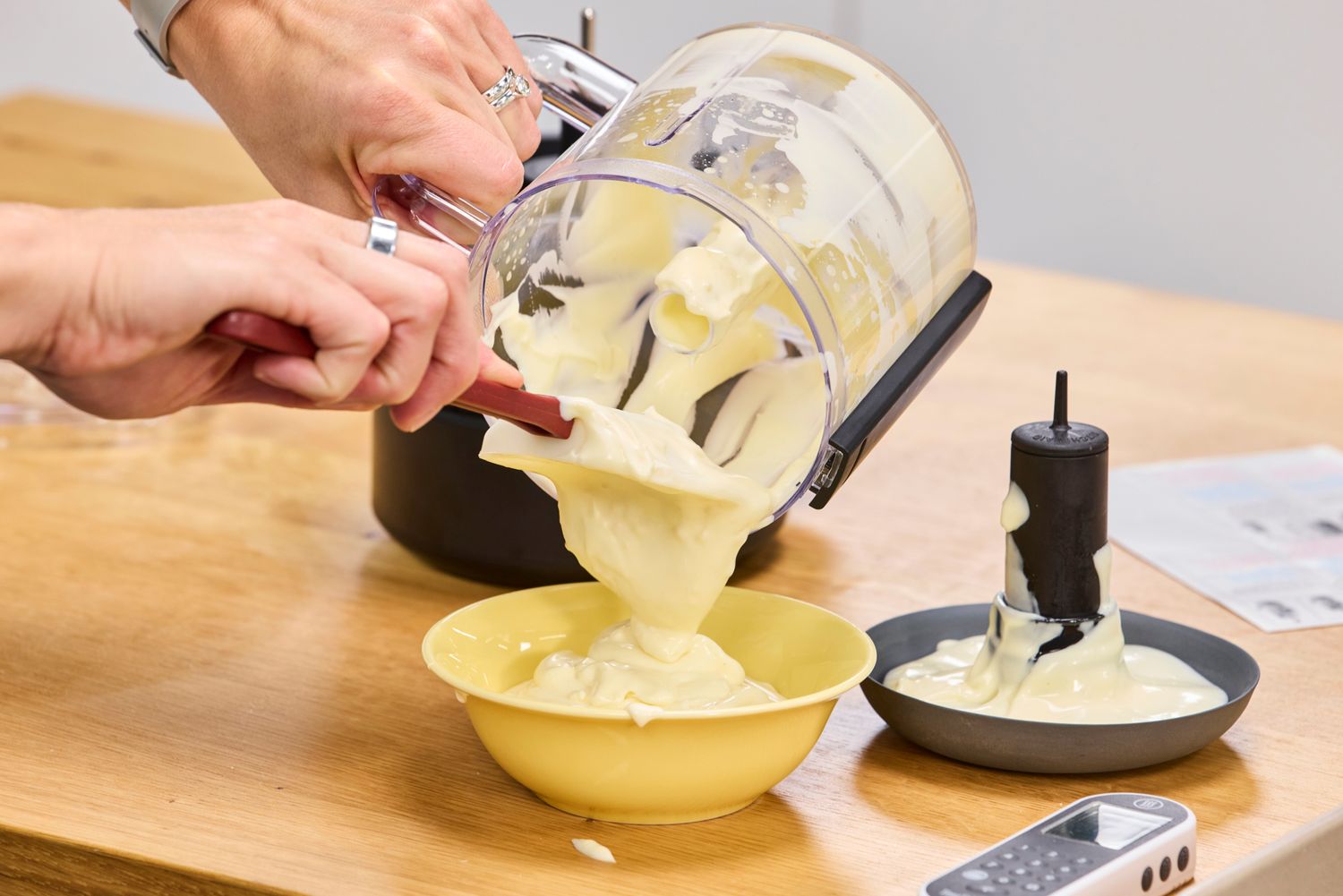 a person scraping out mayo from a food processor