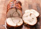 Roast turkey porchetta (turchetta) sliced and on a wooden cutting board.
