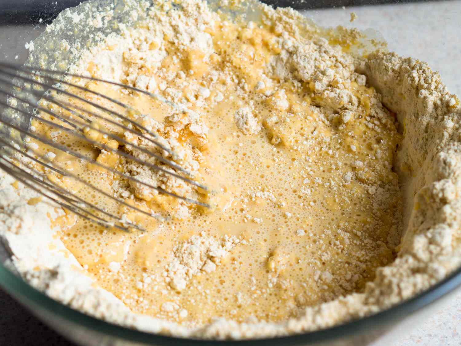 Whisking chickpea flour with water in a mixing bowl.
