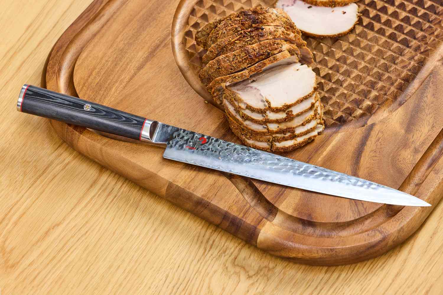 The Miyabi Mizu SG2 9.5 Inch Slicing Knife on a cutting board