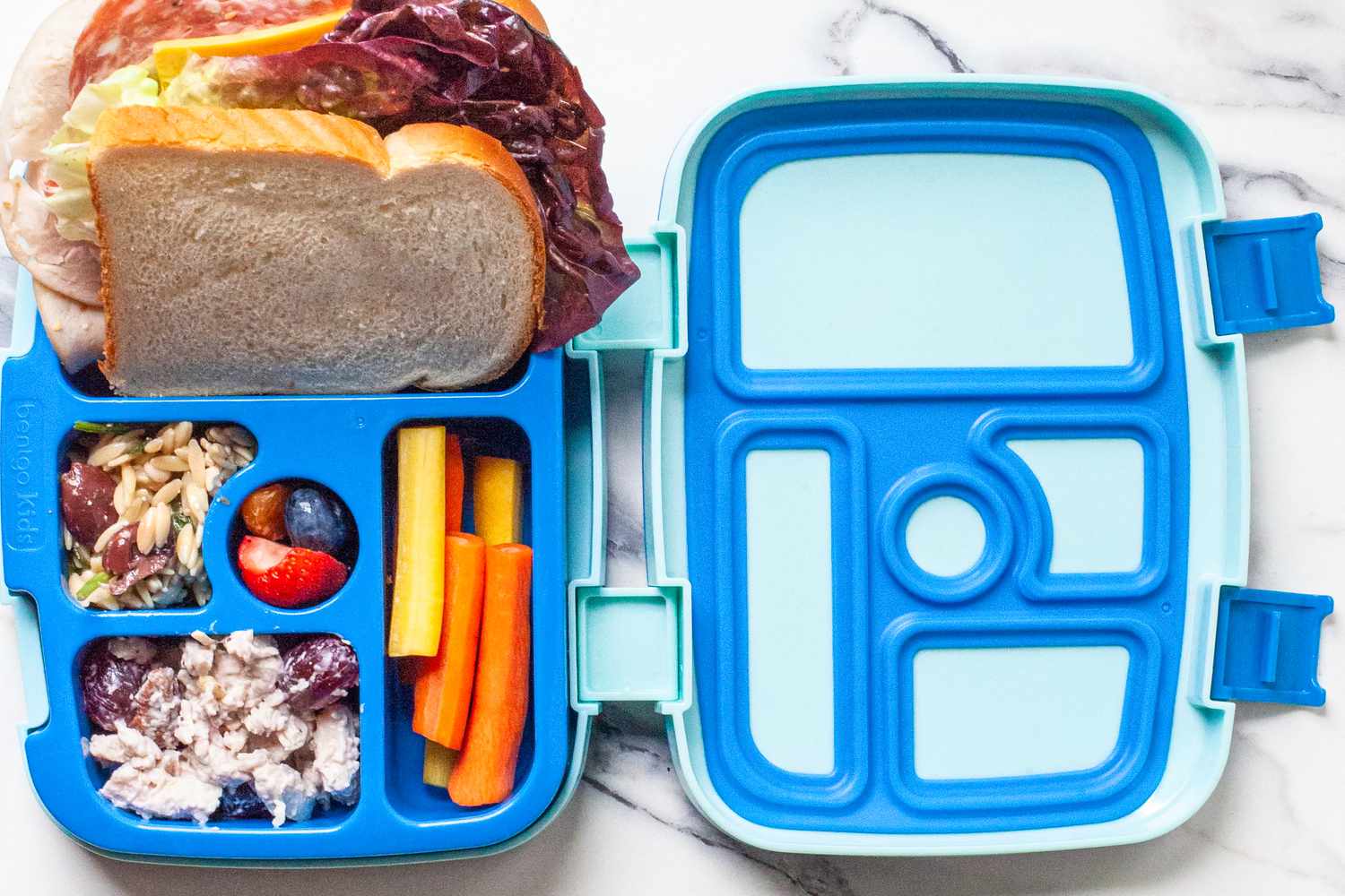 a kids bento box with snacks and a sandwich sticking out