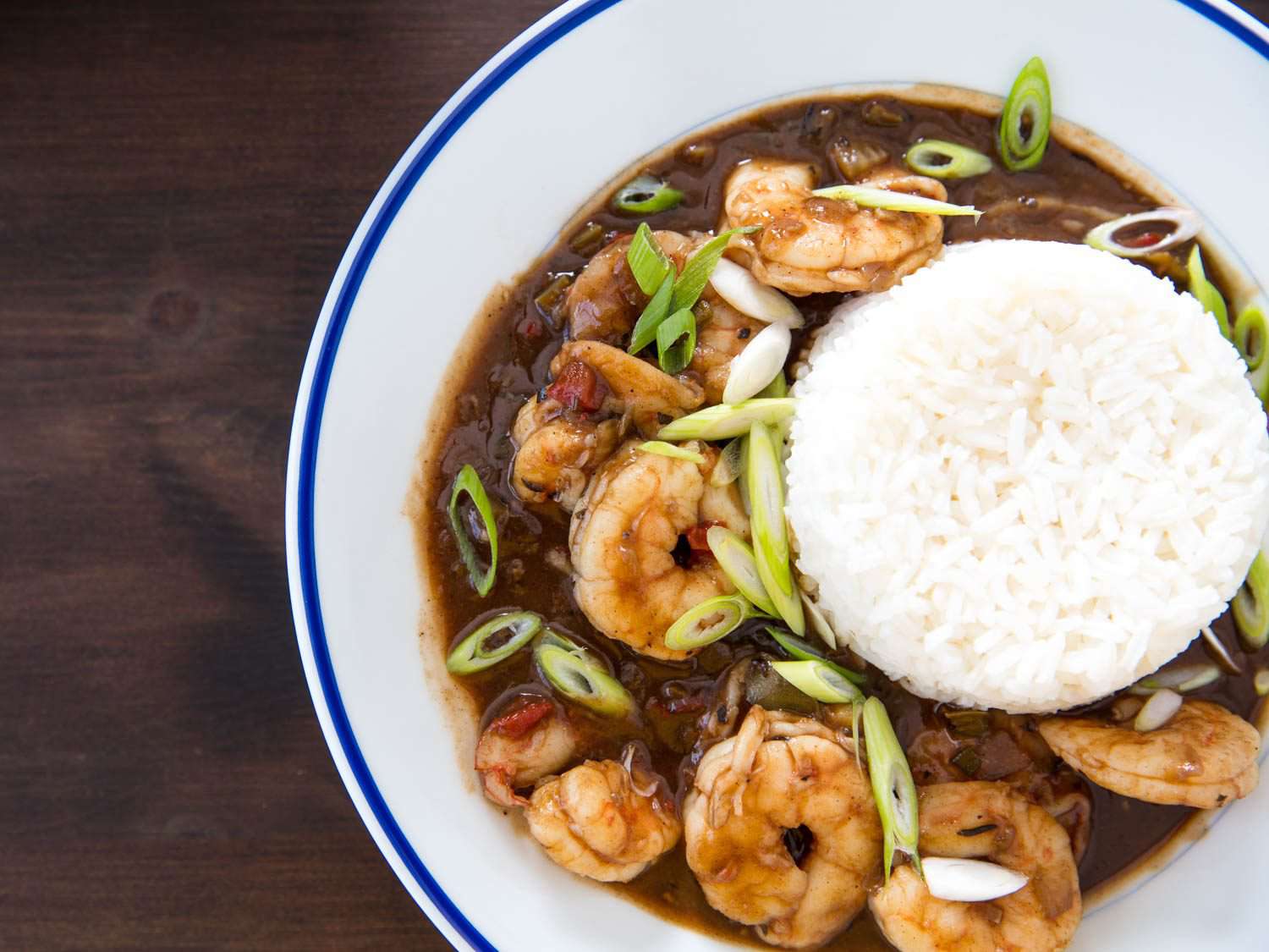 Beauty shot of shrimp etouffee, made with a dark brown roux, on the plate with rice.
