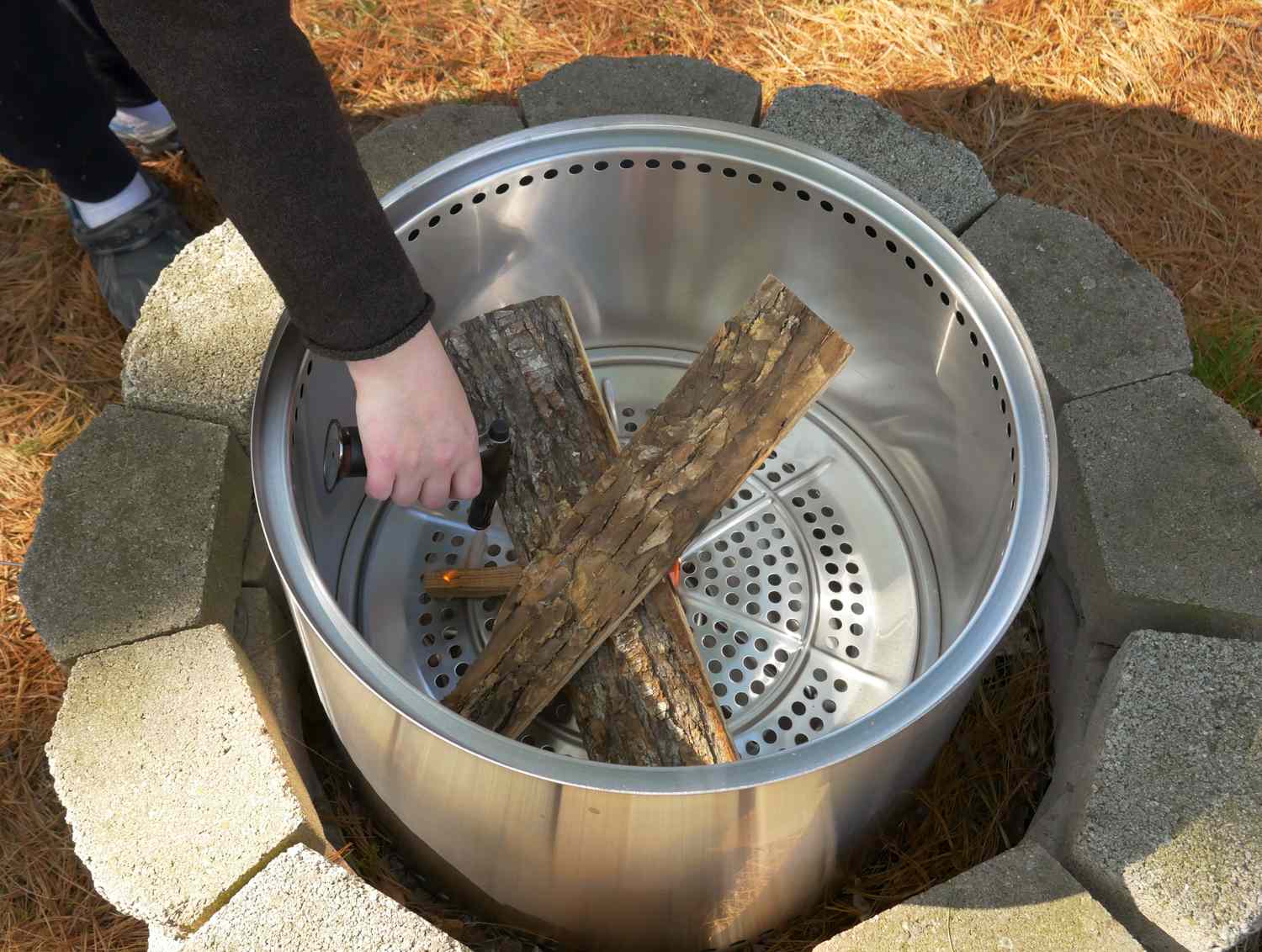 A person using a kitchen torch to light a fire in the Solo Stove fire pit