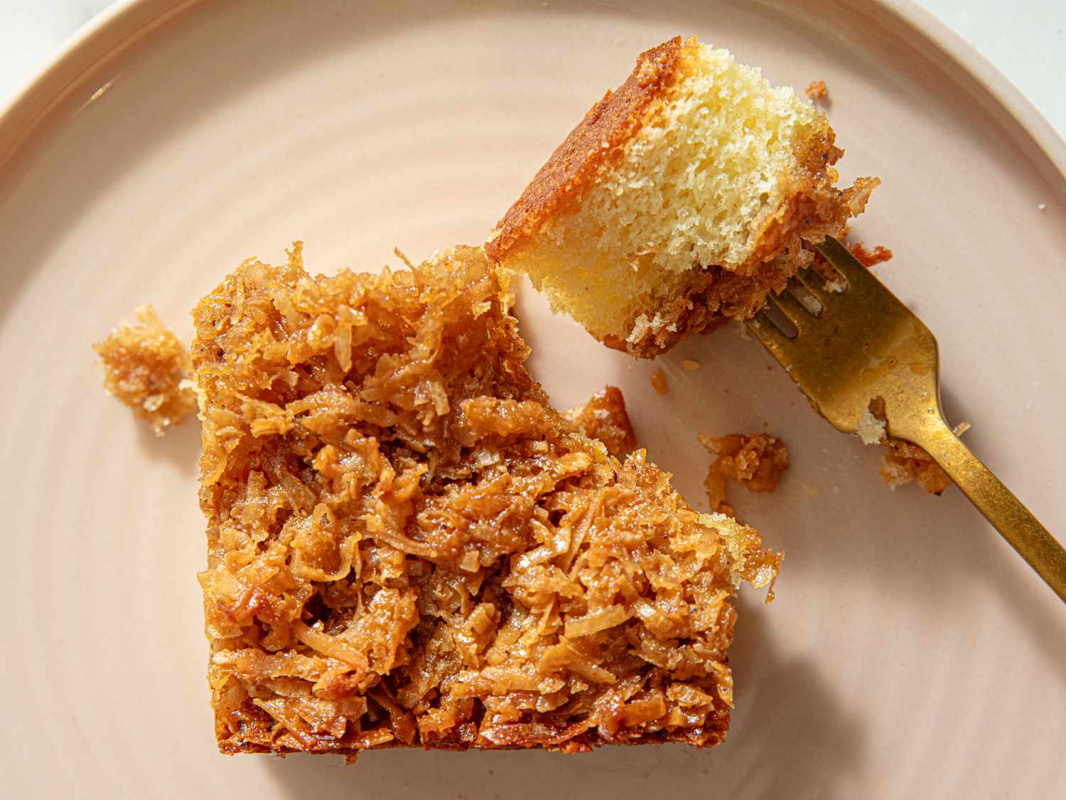 Piece of cake with coconut topping on a plate with a fork