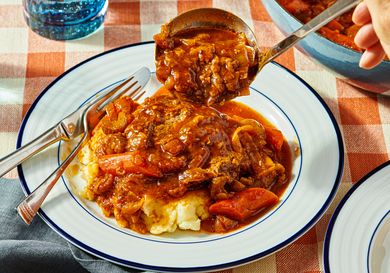 Plate of Swiss steak with mashed potatoes and a serving spoon midaction