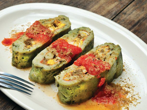 Three slices of Brazo de Reina topped with spoonfuls of tomato frito. 