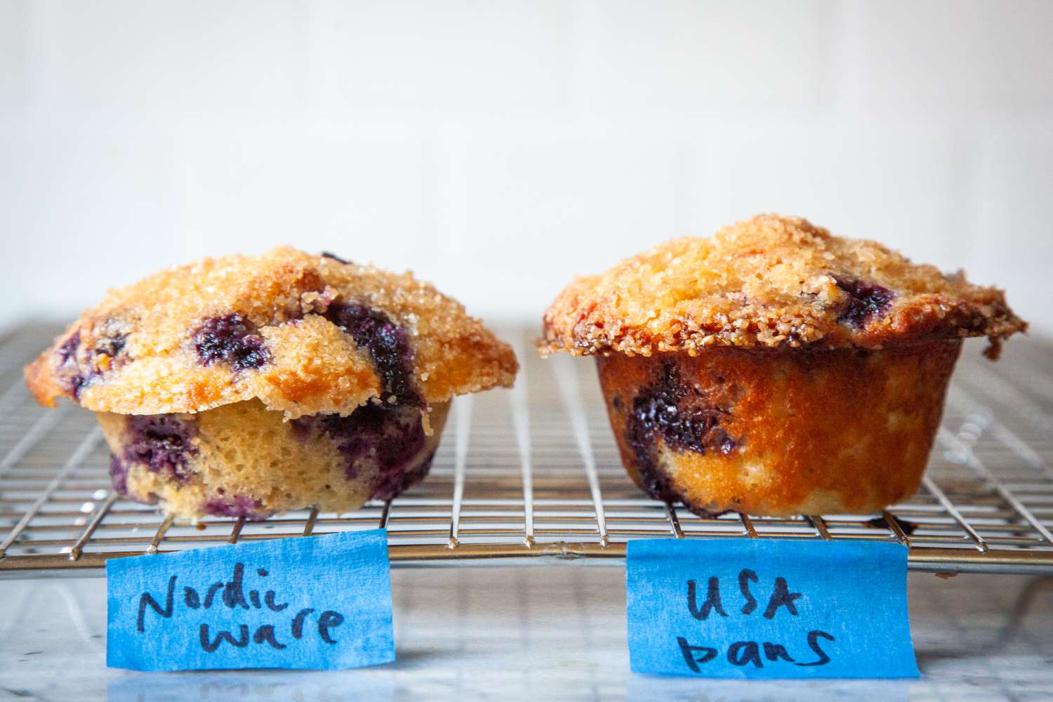 Blueberry muffins made in two different tins on cooling rack