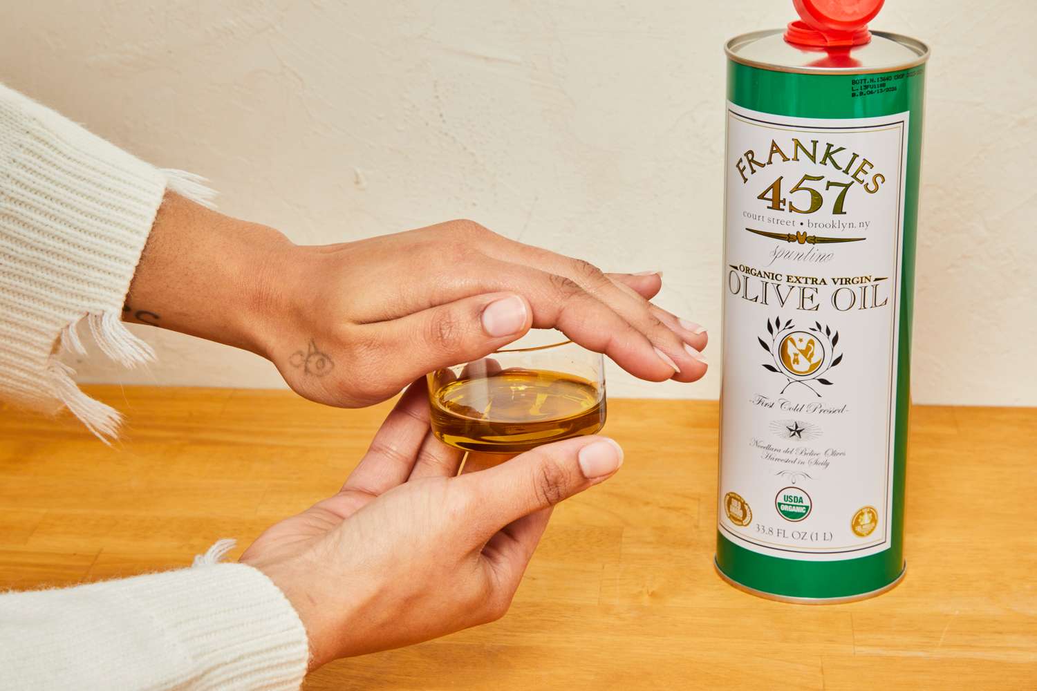 A person covering a cup of olive oil with their hand.