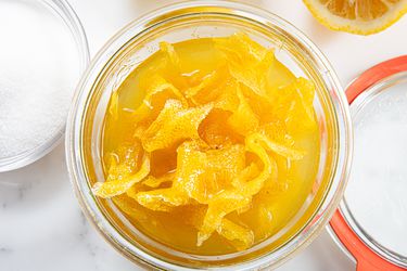 A jar full of bright yellow oleo-saccharum and the candied peels themselves.