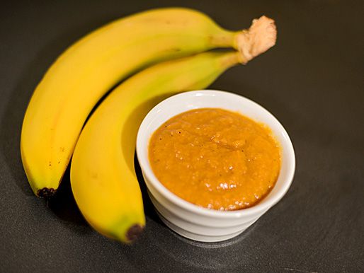 Two bananas next to a bowl of banana ketchup. 