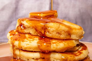 Side view of syrup being poured on pancakes