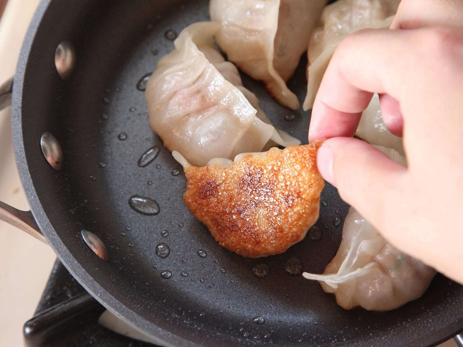 Turning a crisp-bottomed dumpling in pan.
