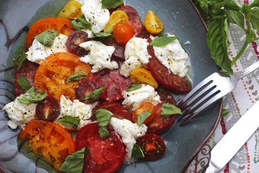 Caprese salad made with assorted colors and sizes of tomatoes