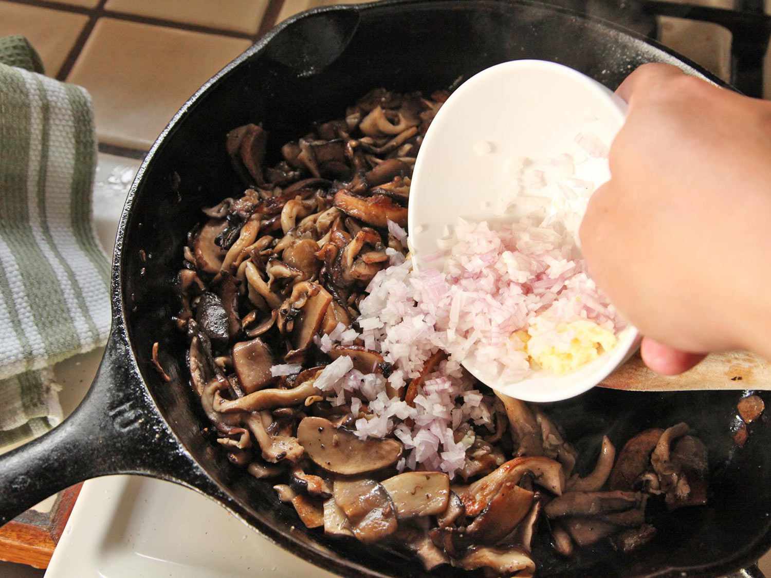 Adding minced shallots and grated garlic to well-browned mushrooms.
