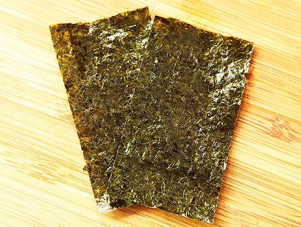 Two pieces of nori resting on a cutting board.