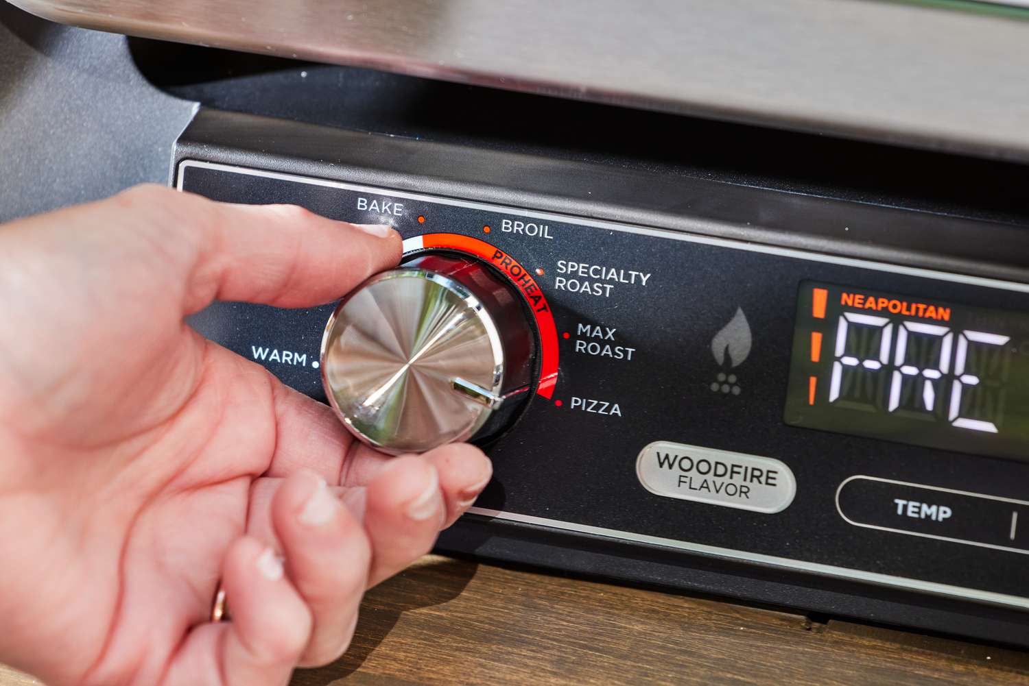 A person turning a nob on the Ninja Woodfire 8-in-1 Outdoor Oven