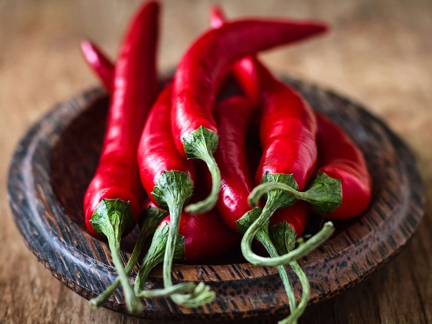 A handful of red chile peppers on a small wood dish.