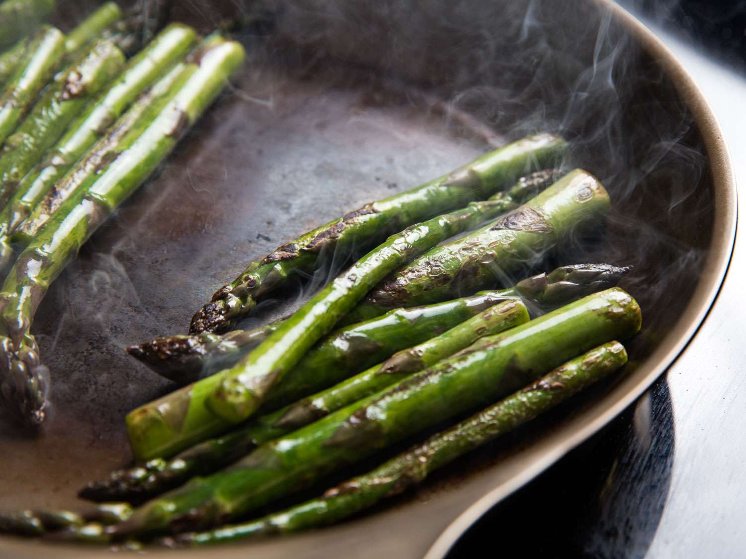 Asparagus sautéing in a pan.
