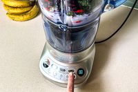 A person adjusting the speed on the Breville Fresh and Furious Blender with smoothie ingredients in the jar