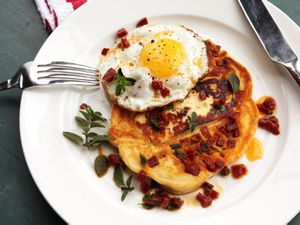 Overhead of a savory chorizo and halloumi pancake topped with a fried egg.