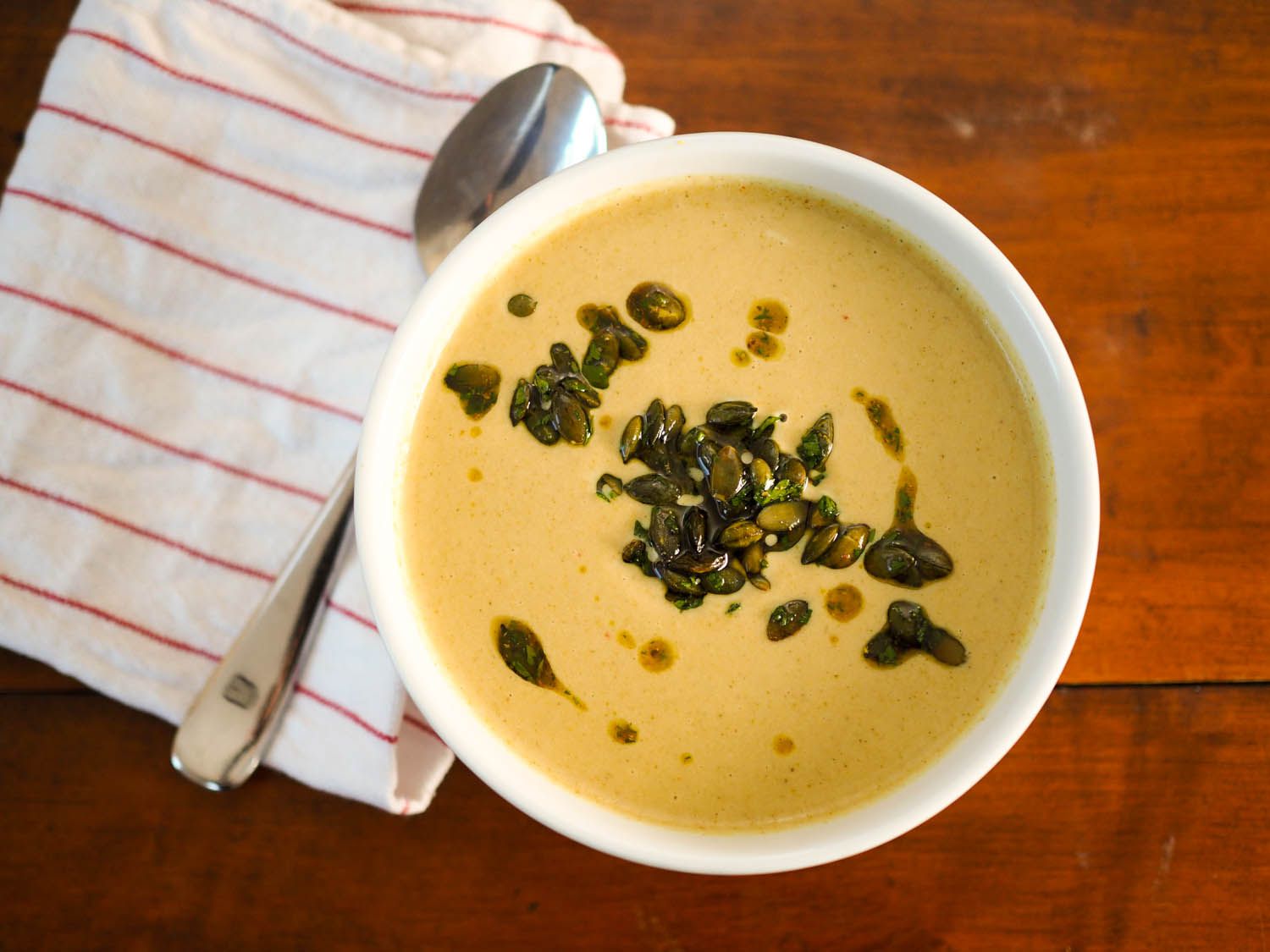 Overh4ead view of the roasted broccoli soup, served in a white bowl on a wooden surface.