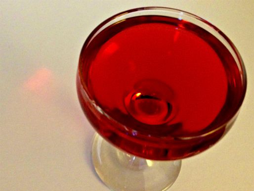 Negroni in a coupe glass on a white table.
