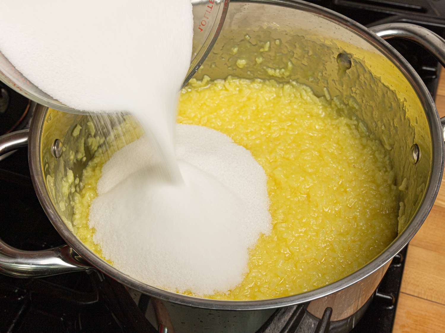 Overhead view of adding sugar to rice mixture