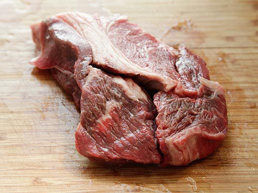 Beef chuck on a wooden cutting board. 