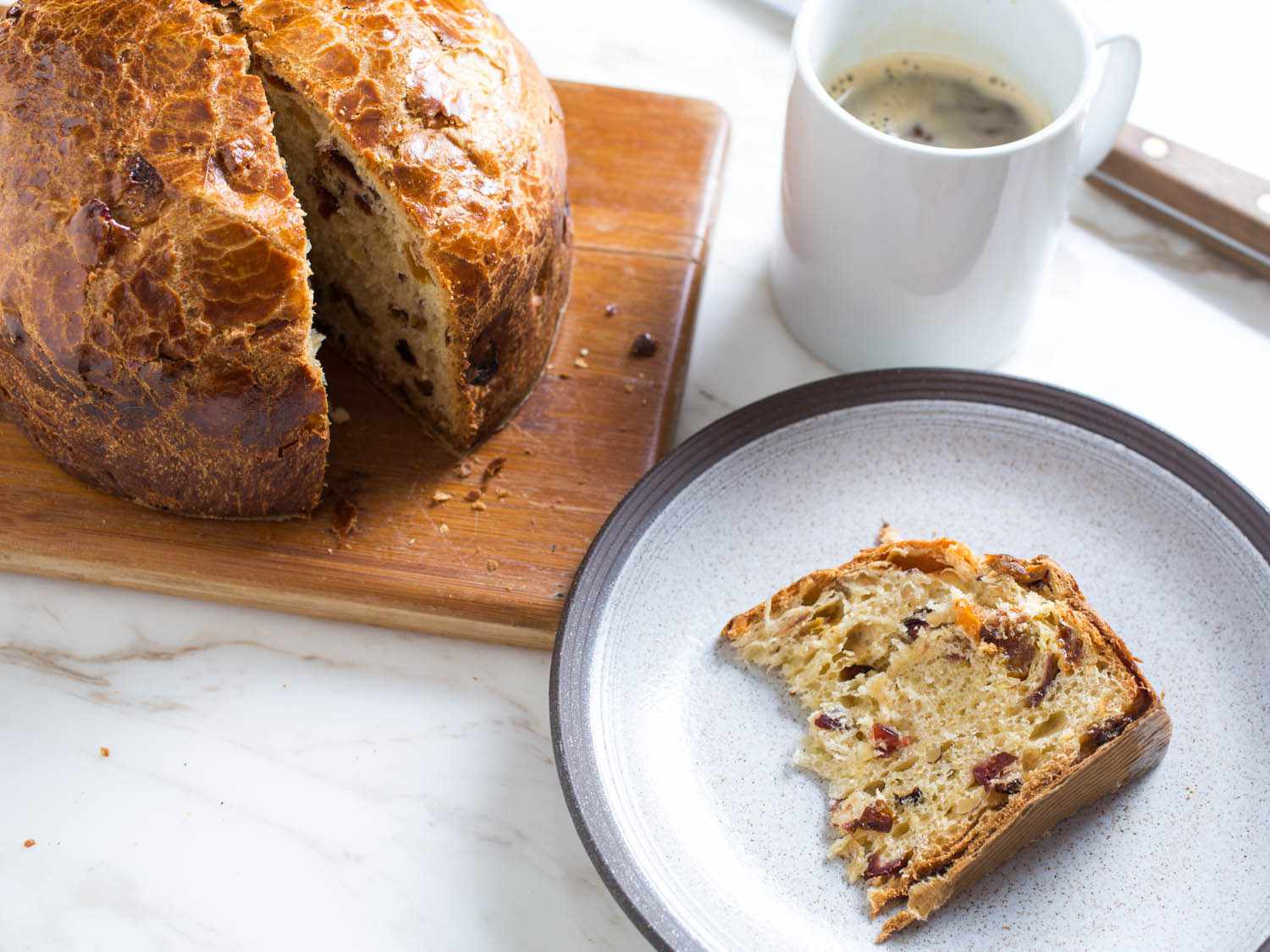 Slice of panettone on a plate next to a cup of coffee