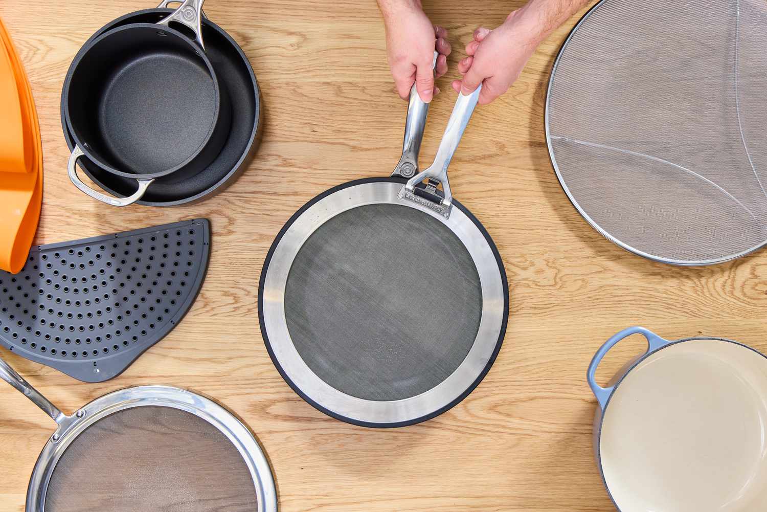 a person placing the le creuset splatter screen on a skillet