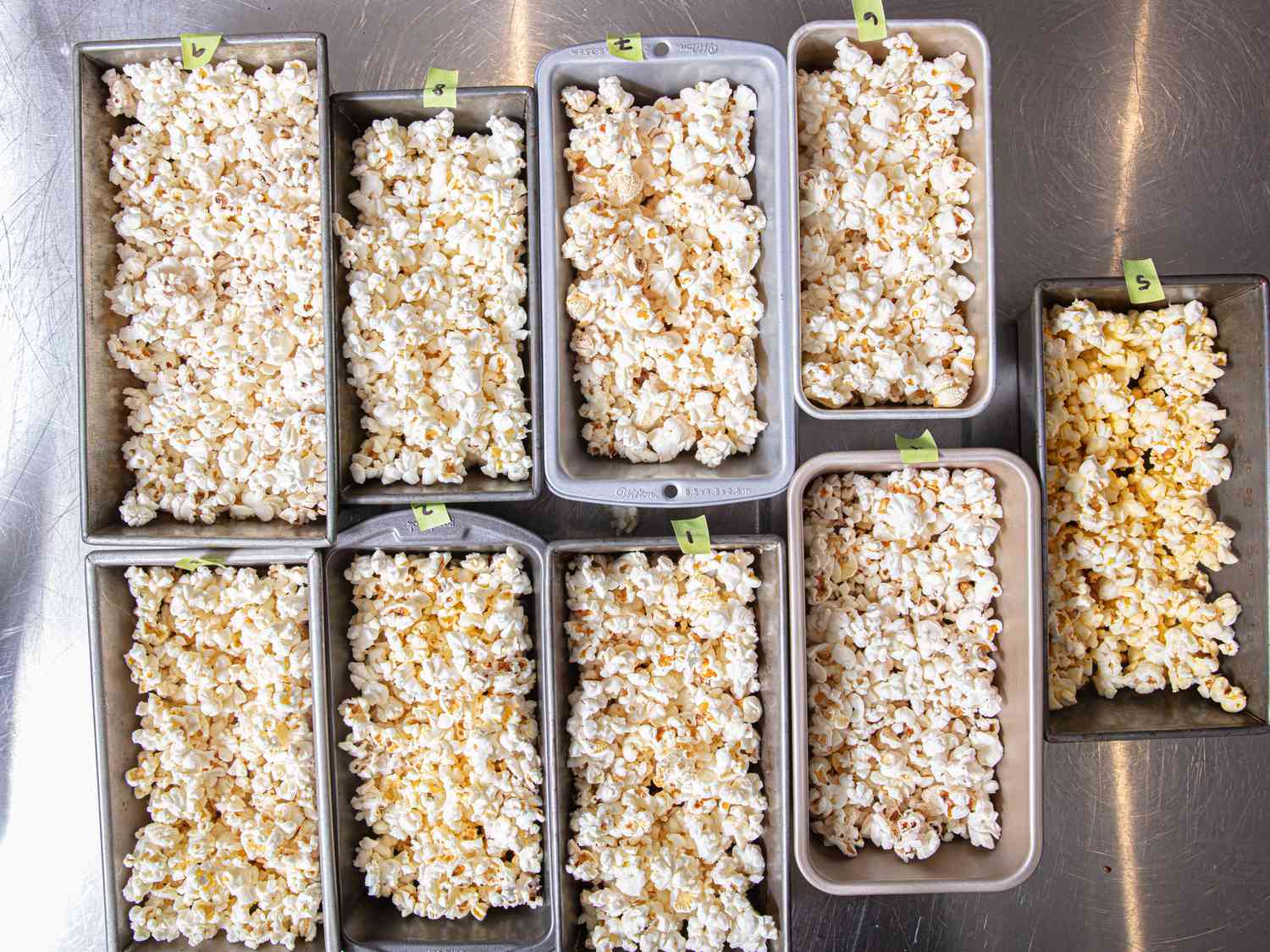 A variety of serving trays filled with popcorn arranged on a metallic surface
