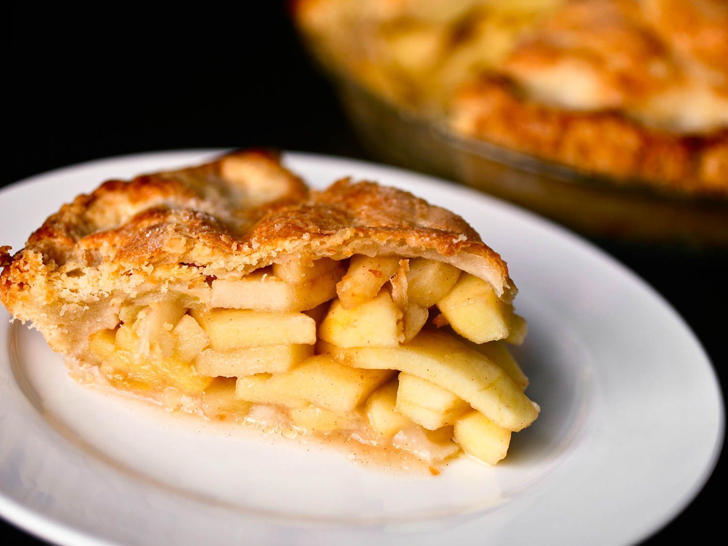 Close-up of apple pie in a glass dish, with a wedge cut from it