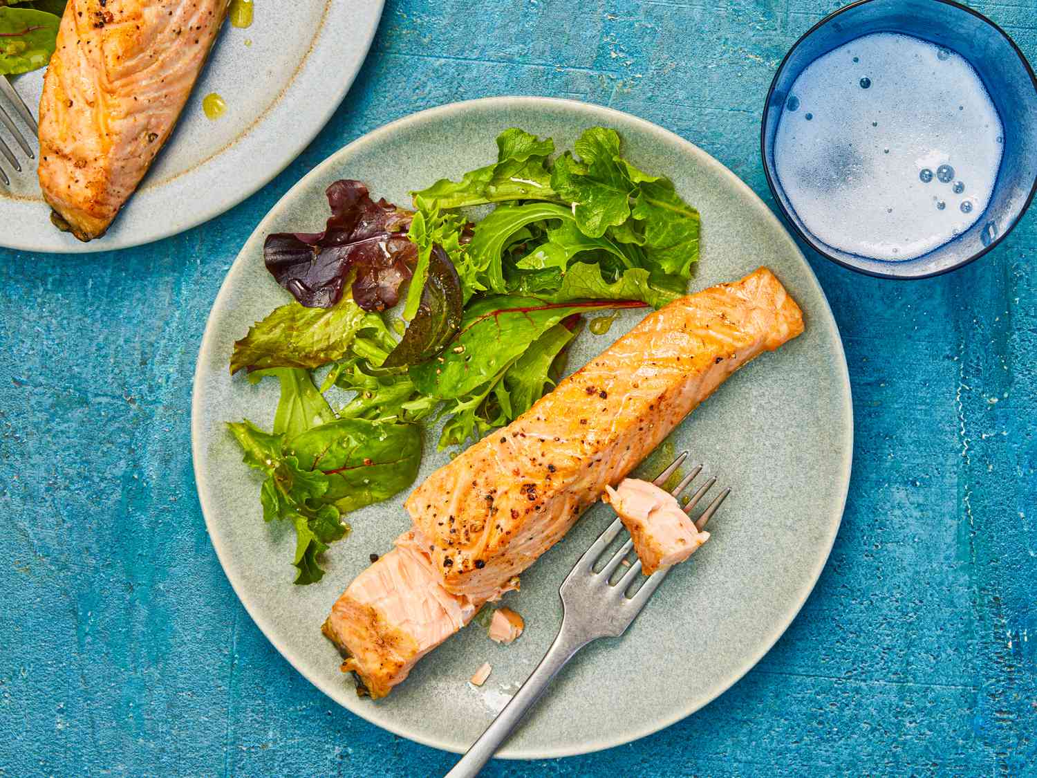 Overhead view of air-fryer salmon, served on an earthenware plate with a simple green salad.
