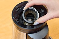 A person removes a part from the OXO Brew Conical Burr Coffee Grinder
