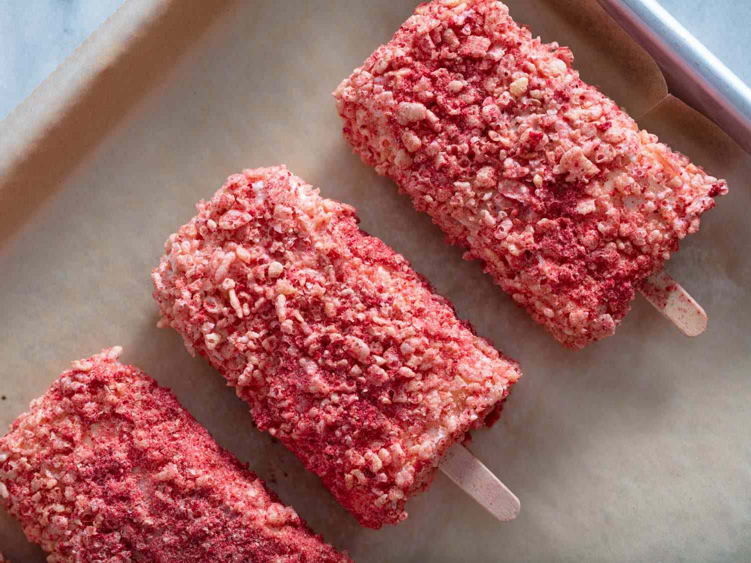The coated strawberry shortcake bars are transferred to a freshly lined baking sheet.