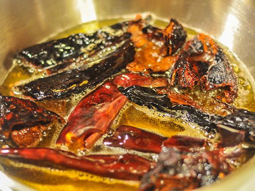 Dried chiles cooking in hot oil.
