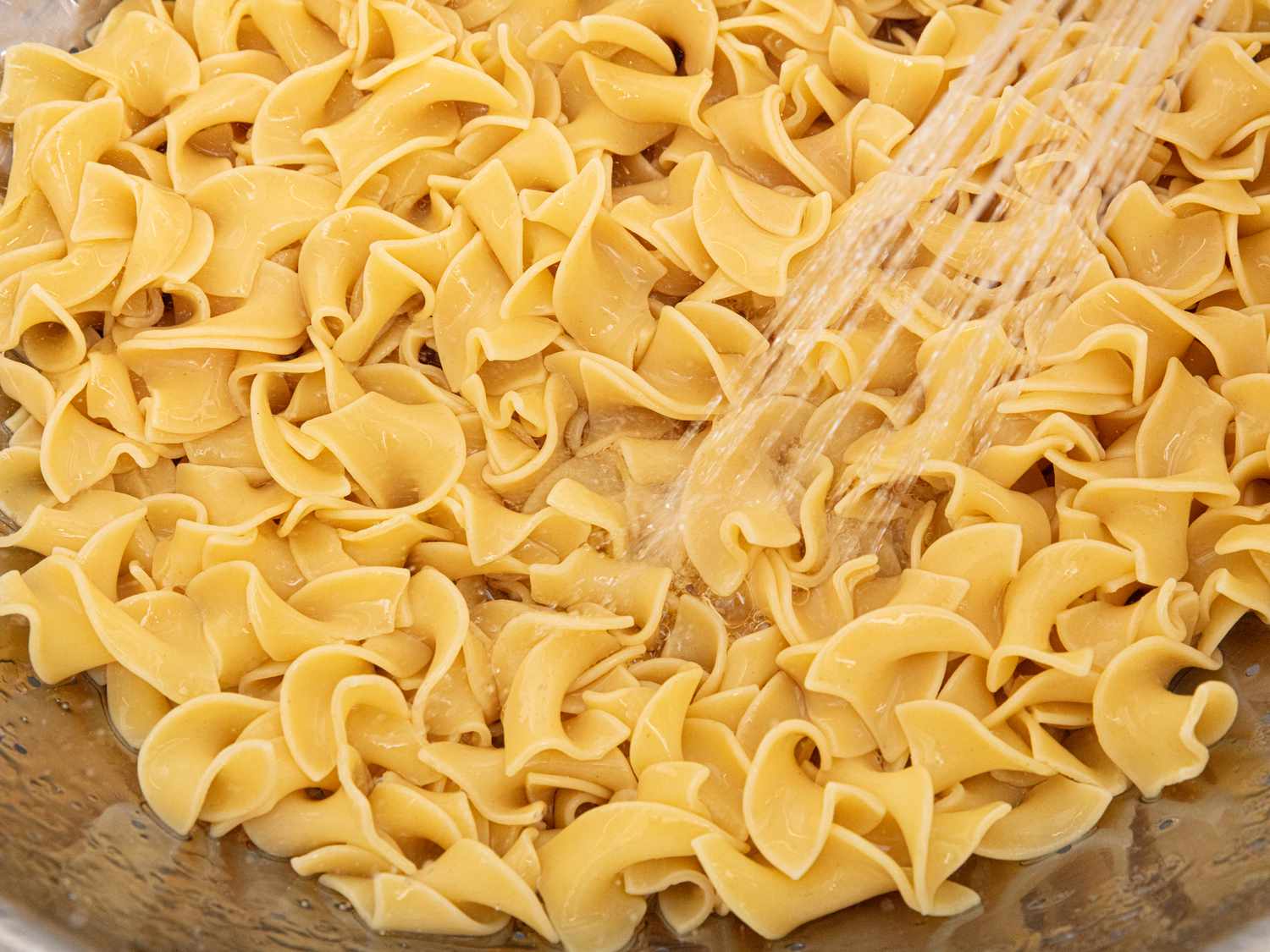 Noodles being rinsed and drained after boiling 