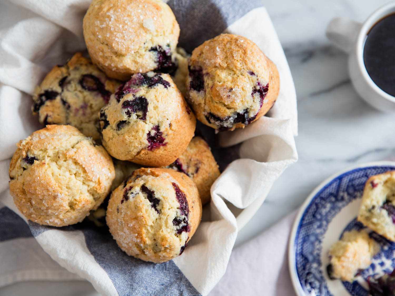 A cloth-lined basket of blueberry muffins.