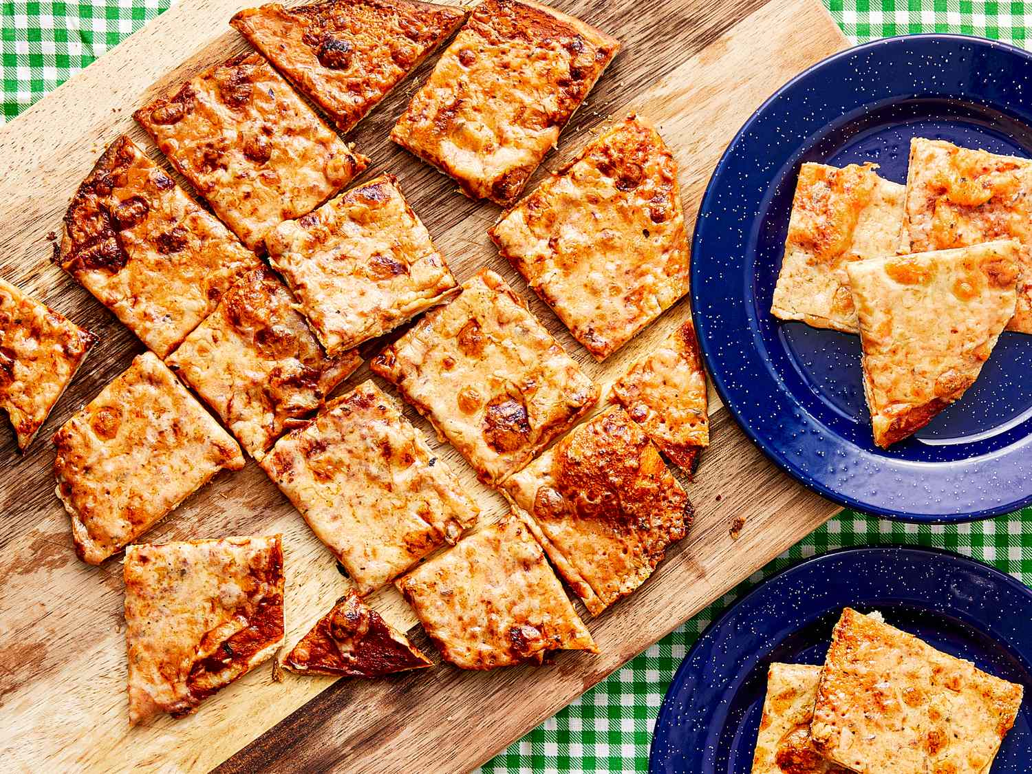 Slices of St Louisstyle pizza served on a wooden board and plates