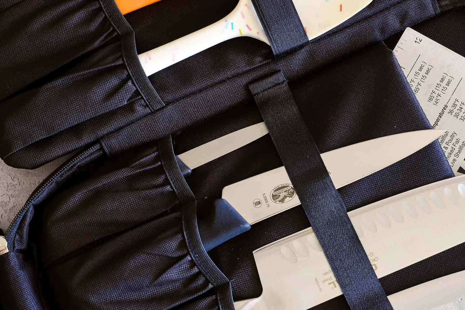 Knives stored in a black knife roll with some handles and blades partially visible