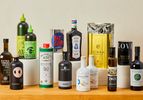 Numerous bottles of olive oil on a wooden countertop.