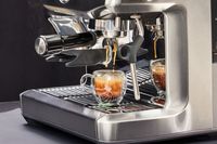 Close up of the Breville Barista Express Impress brewing an espresso into a glass cup 